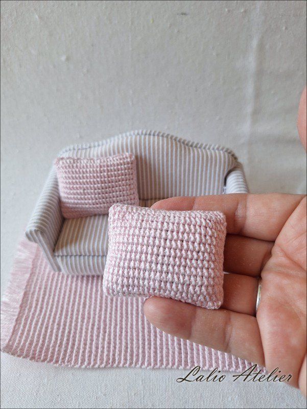 Handmade pink miniature cushion decorating a dollhouse sofa in 1:12 scale