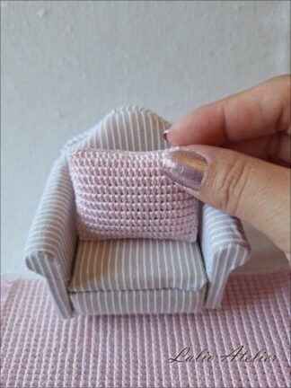 Handmade pink miniature cushion decorating a dollhouse sofa in 1:12 scale