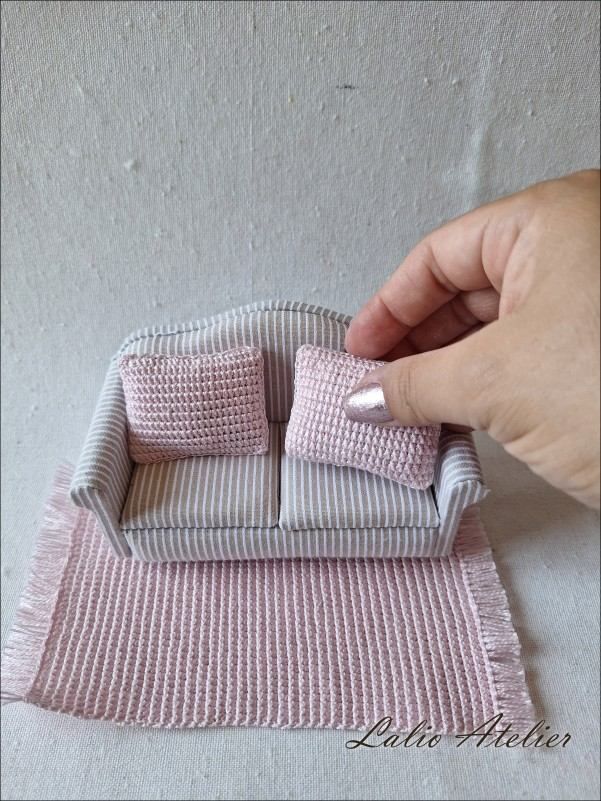 Handmade pink miniature cushion decorating a dollhouse sofa in 1:12 scale
