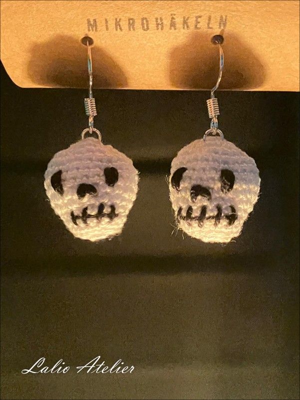 Detailaufnahme der schwarzen Stickerei auf den weißen Totenkopf-Ohrringen.