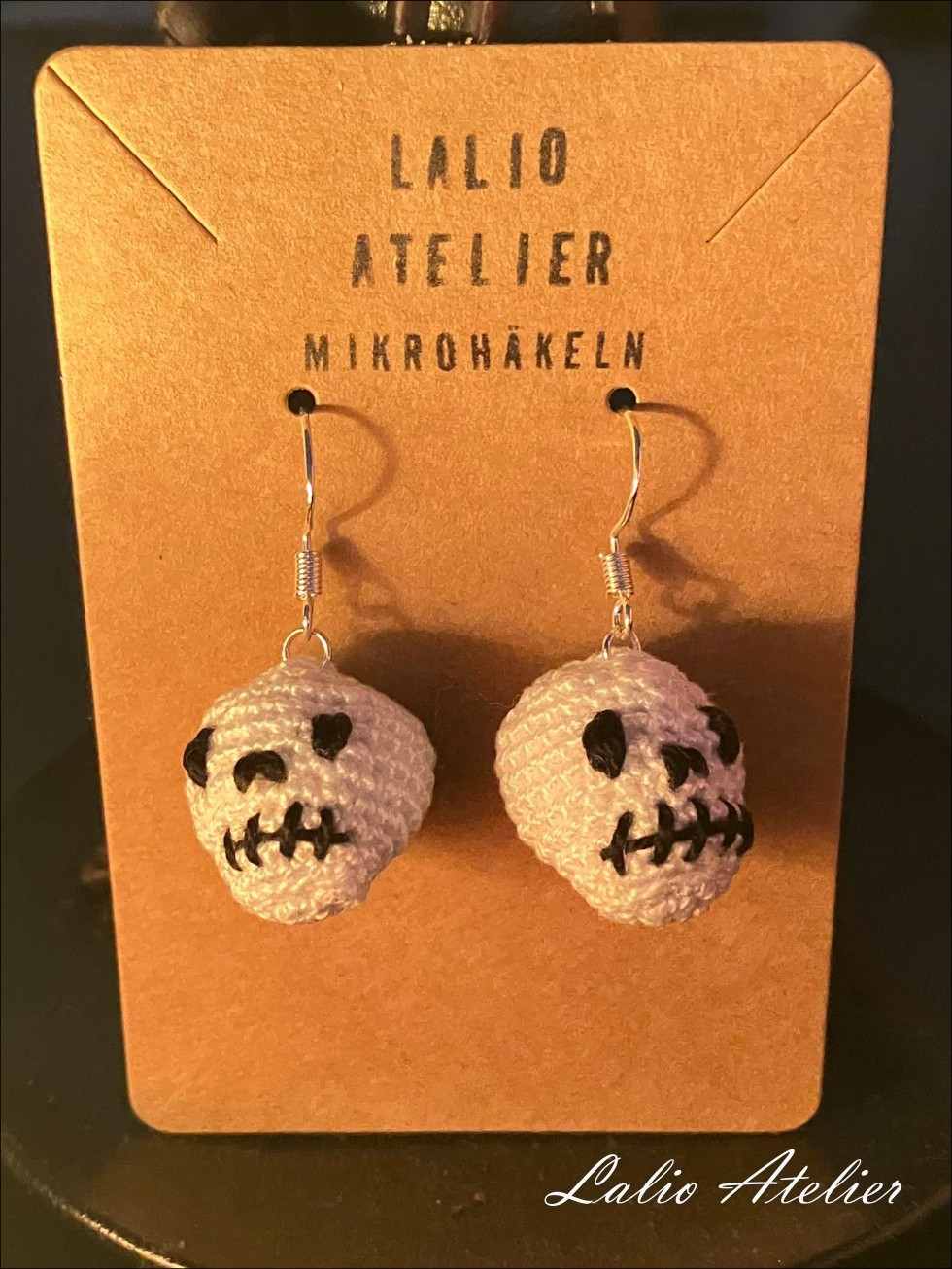 Totenkopf-Ohrringe aus Baumwolle auf rustikalem Hintergrund – handgefertigt von Lalio Atelier.