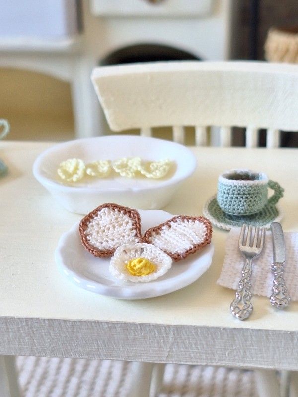 Micro crochet fried egg displayed with miniature coffee mug and breakfast accessories