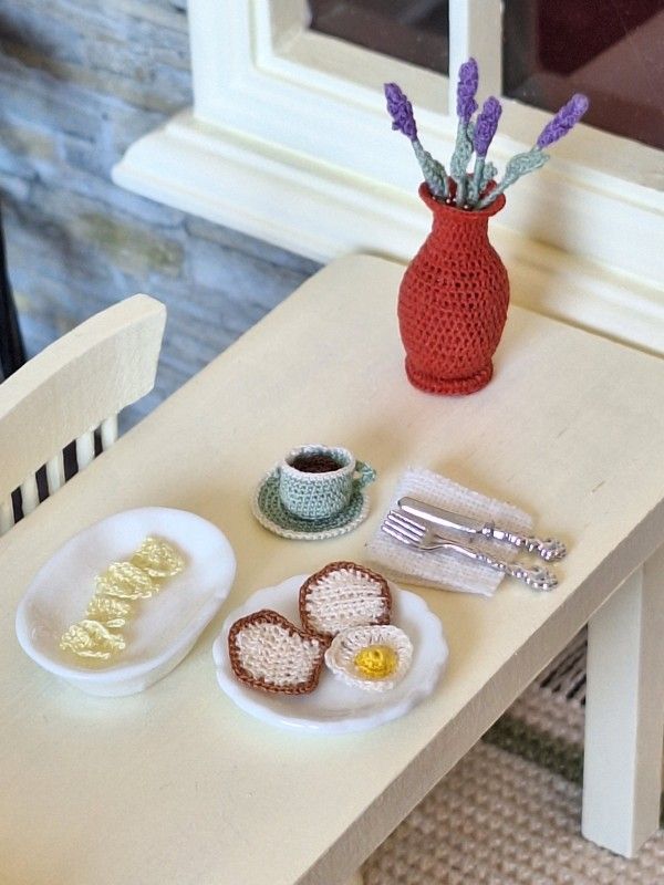 Micro crochet fried egg displayed with miniature coffee mug and breakfast accessories