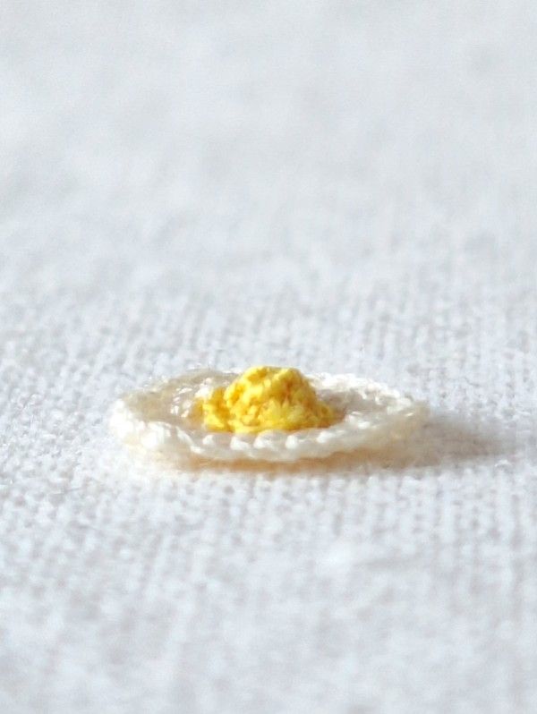 Side view of a handmade micro crochet fried egg showing the raised yolk