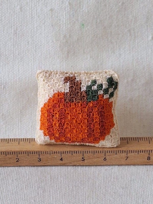 Tiny handmade pumpkin cushion displayed in a 1:12 scale miniature room