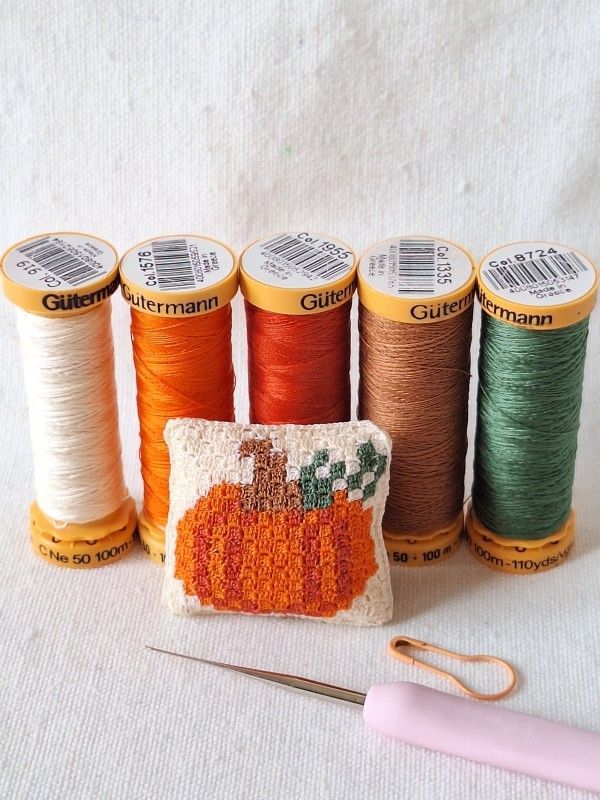 Sewing cotton threads in autumn colours used to crochet the miniature pumpkin cushion